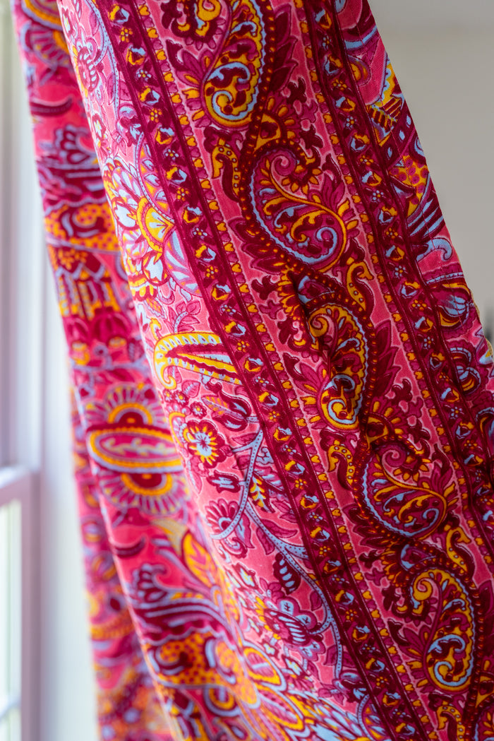 Close-up of a vibrant pink and orange paisley fabric - this displays the solid fabric that lines the back side of the patchwork curtain