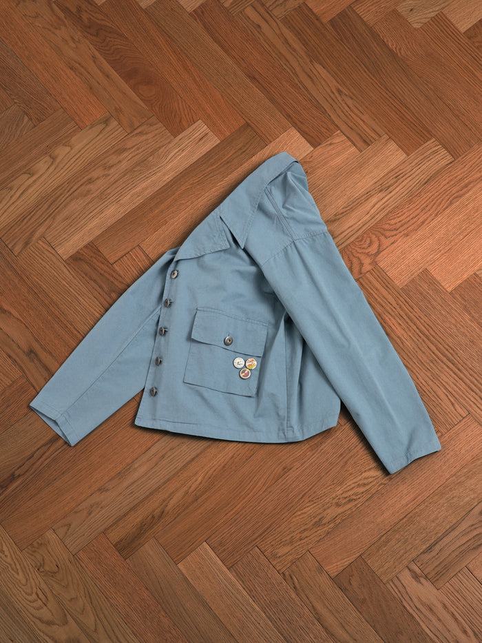 A vintage Found Patina Work Jacket laying on a wooden floor.