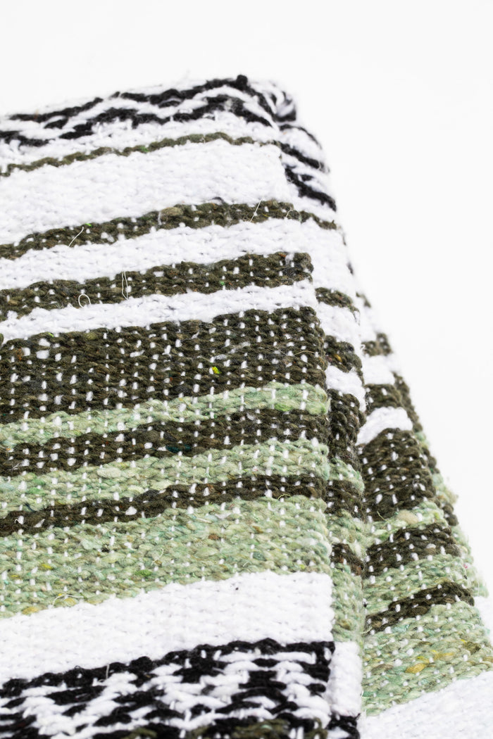 Striped recycled blanket with green, white, and black pattern on a white background