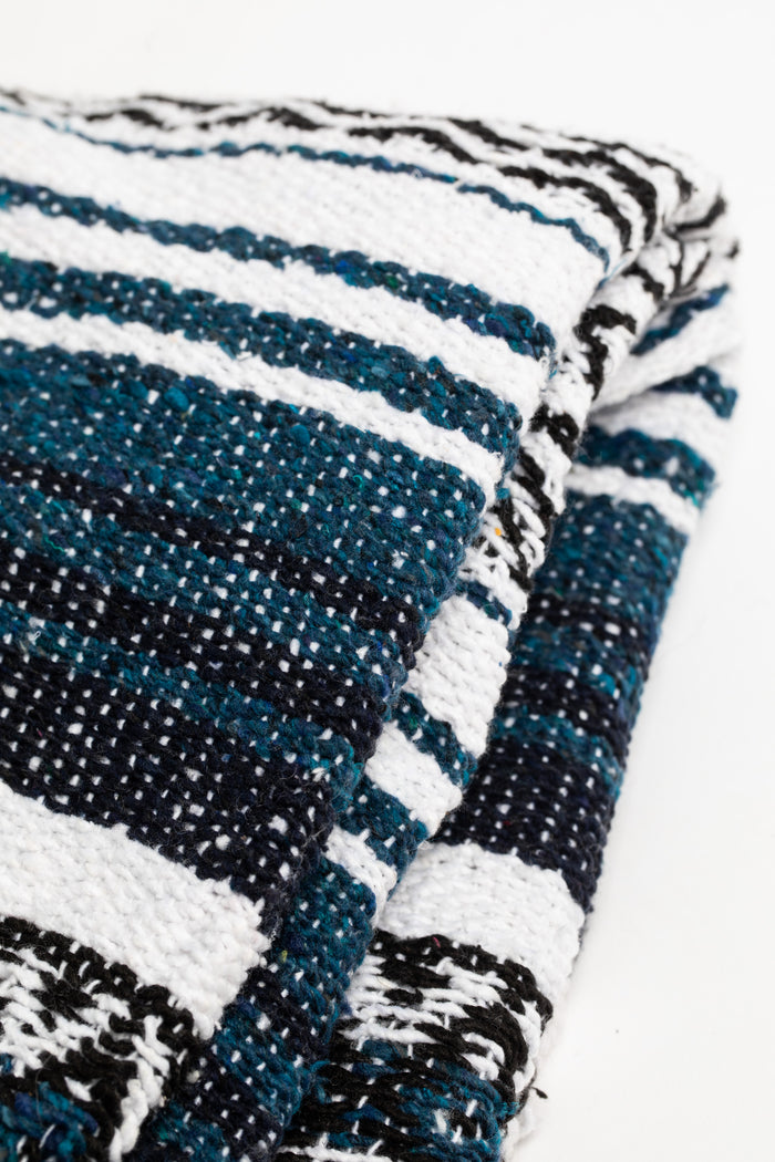 Woven recycled blanket with blue, white, and black pattern on a white background