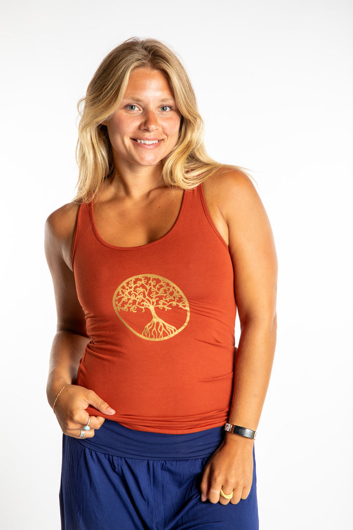 Sophie wearing a Small orange Tree of Life tank top with a tree design in Adobe