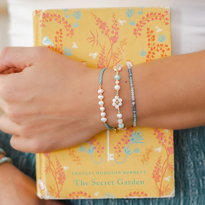 Seafoam Mermaids Pearl Bracelet, stacked over a book