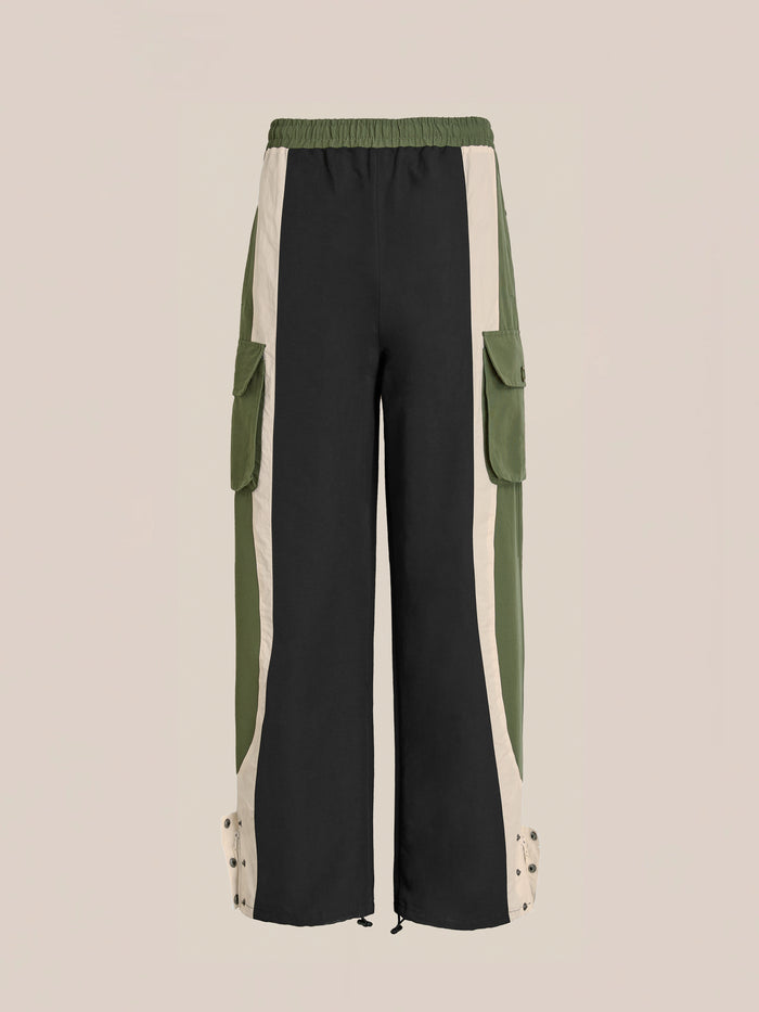 The Found Sporting Club Track Pants blend vintage athletic style with utility, featuring a unisex fit, wide legs, elastic waistband, black/olive/beige color-blocking, side pockets, and snap buttons at the ankles.