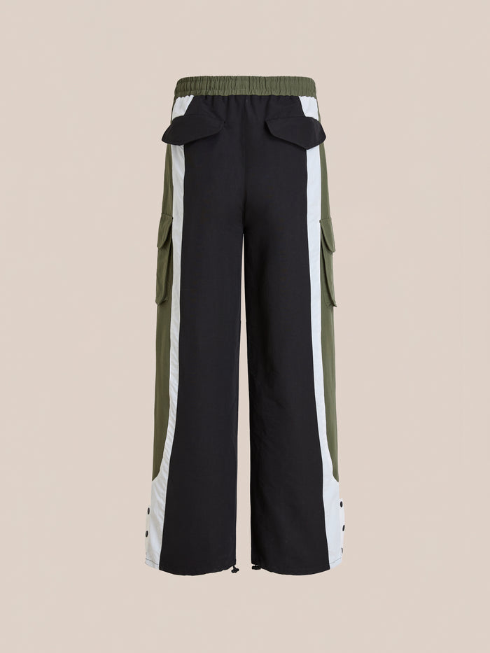Found Sporting Club Track Pants: unisex wide-leg black track pants with adjustable waistband, white side stripes, olive green panels, cargo and back flap pockets—sportswear style shown from the back.