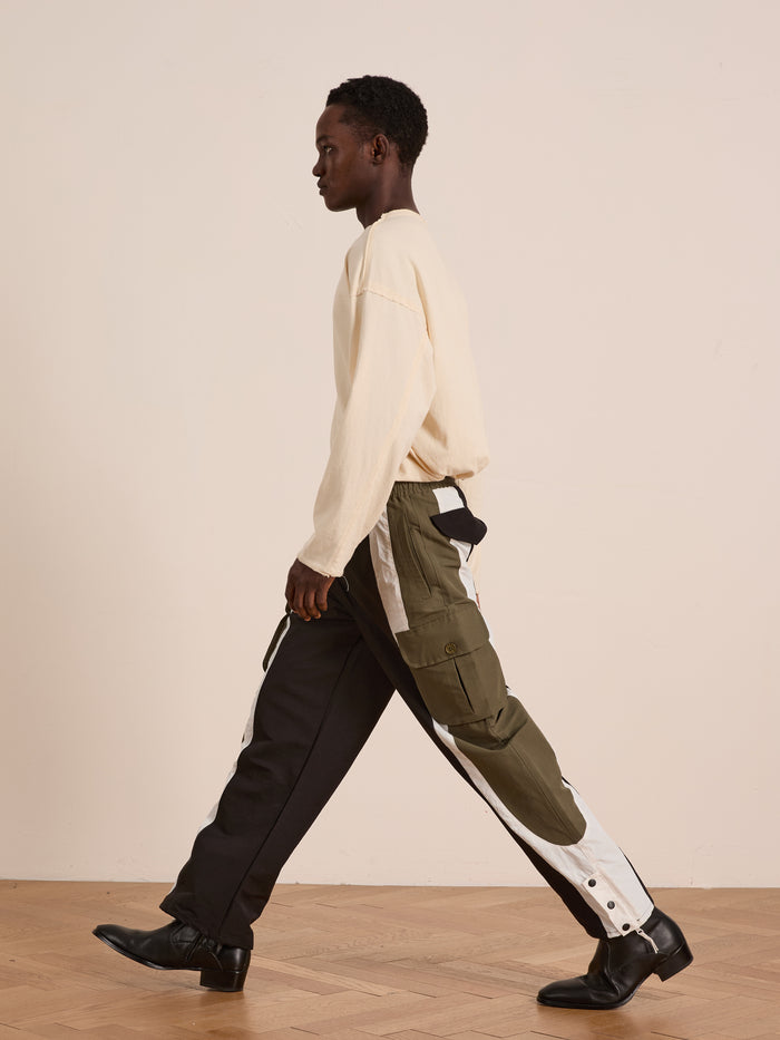 A person in a cream long-sleeve shirt and Found Sporting Club Track Pants with an adjustable waistband walks indoors on a wooden floor against a plain light wall.