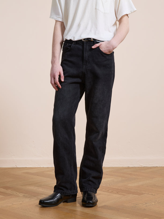 Someone wearing Found Straight Leg Jeans with a white short-sleeve t-shirt, belt, and black shoes stands on a wooden floor against a neutral background.
