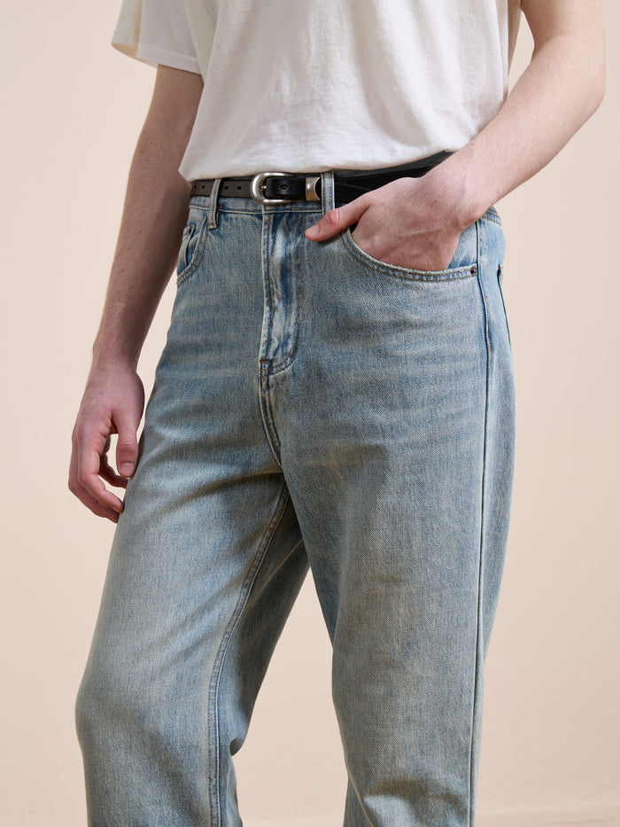A person in Found Straight Leg Jeans and a white t-shirt, styled with a black belt and one hand in their pocket, stands against a neutral background.
