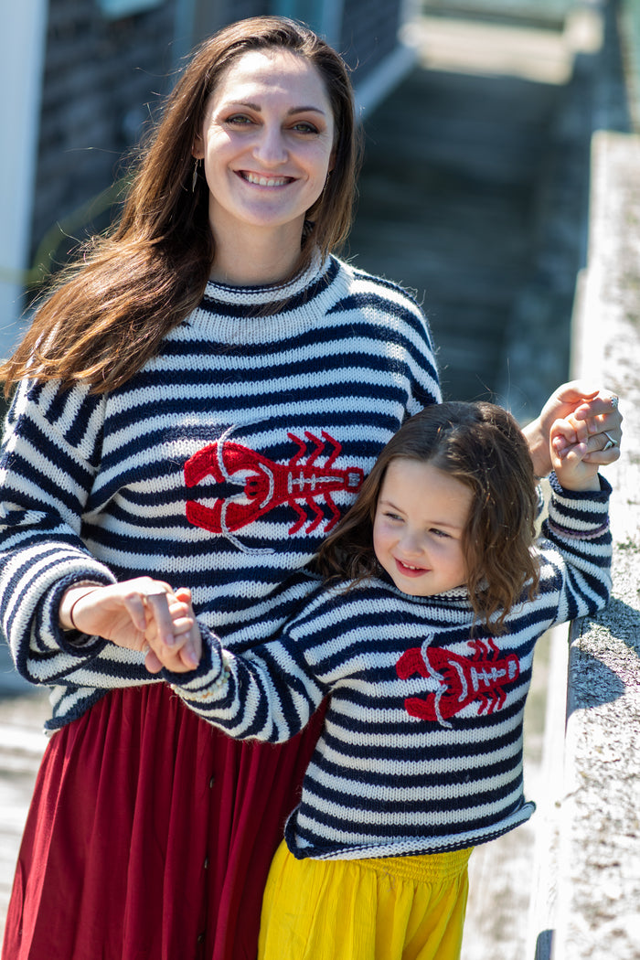 Lilly is wearing a kids lobster sweater. Morgaine is wearing a striped lobster alpaca sweater.
