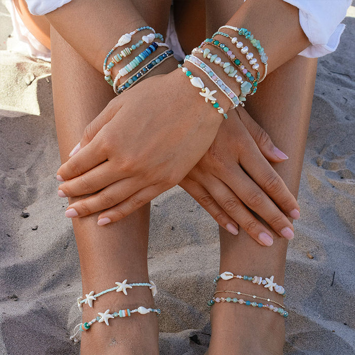 Teal Horizons Healing Bracelet, worn seated on the sand