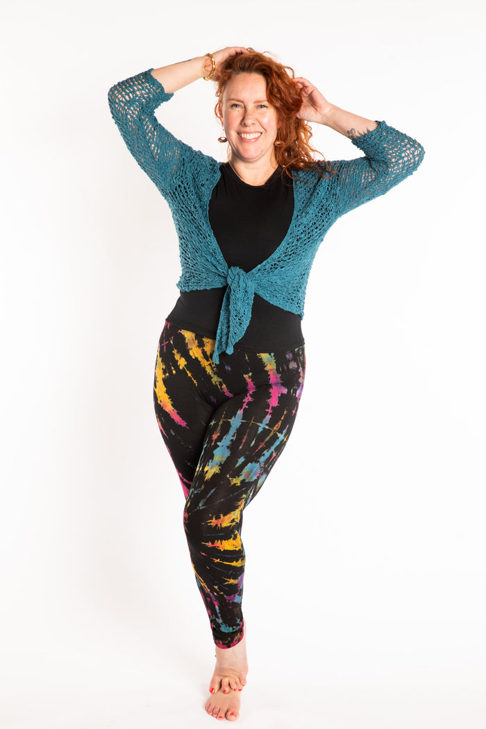 Maggie is wearing the size M/L Black Rainbow Tie Dye Leggings, size L Chara Crew Neck Top in Black and Talia Loose Weave Wrap Cardigan in Teal