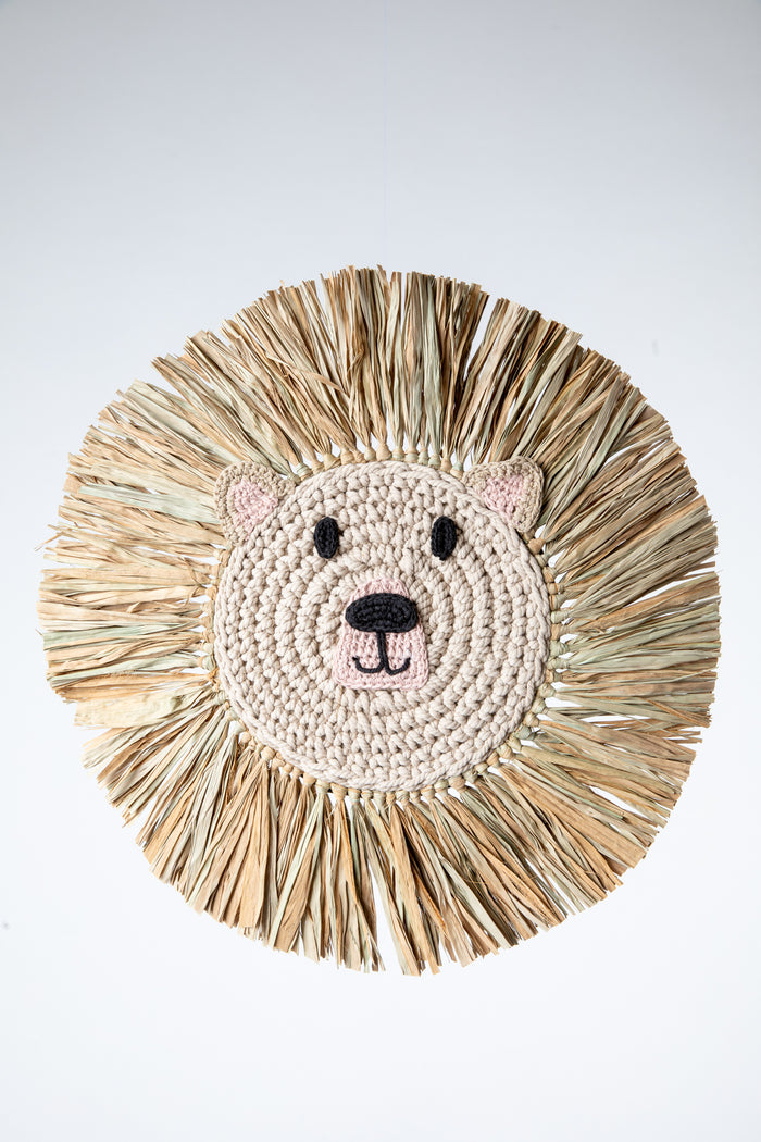 Macrame wall hanging in the shape of a bear's face with a mane made from palm fronds.