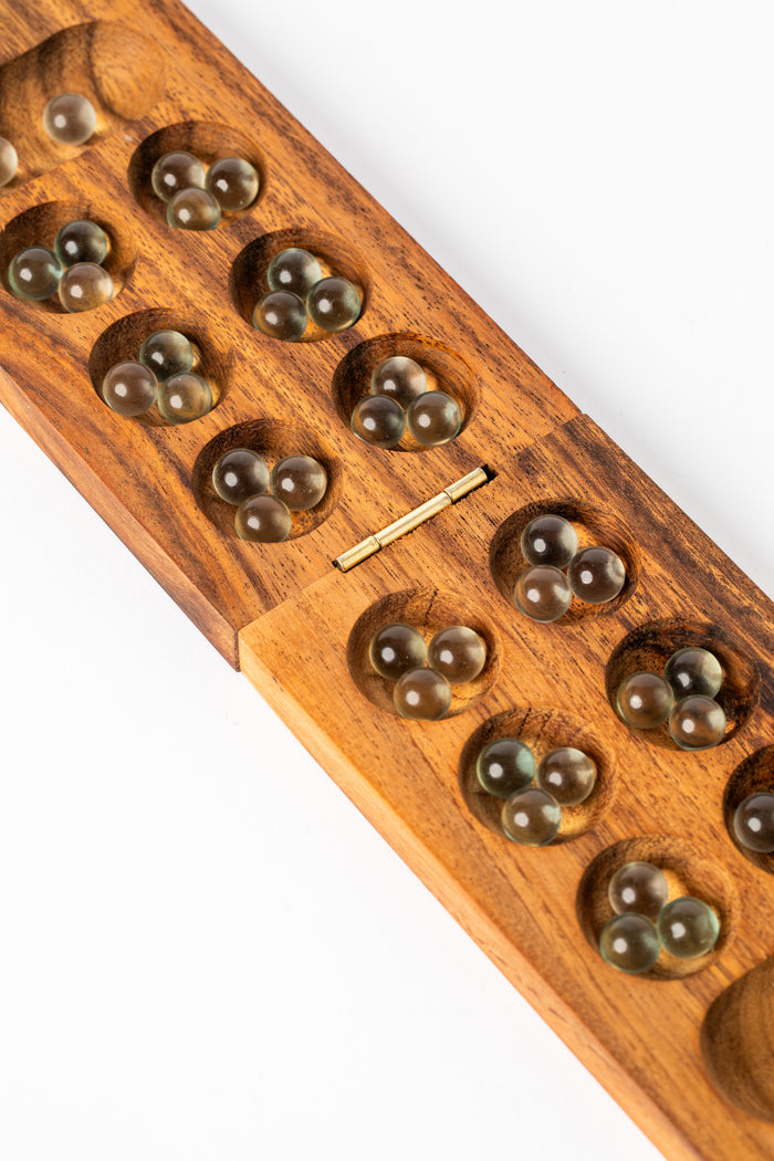 Handmade wooden mancala game board with natural wood grain and glass marbles — artisan board game from Thailand.