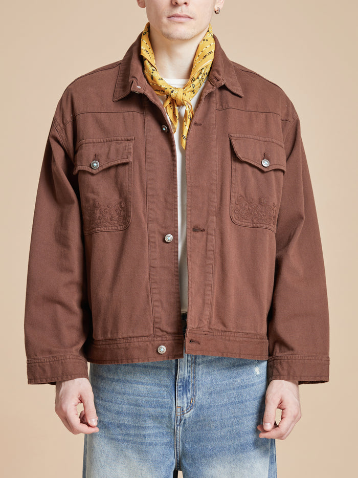A man wearing a brown jacket and a Found Yellow Western Bandana scarf.