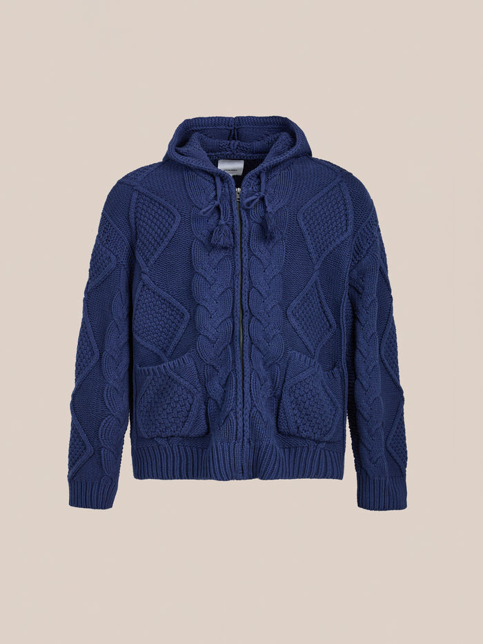 The Found Zip Up Cable Knit Hoodie is a unisex navy blue zip-up sweater with a drawstring hood, shown on a plain light beige background.